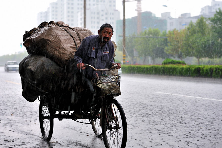 收购废品的老人在雨中艰难前行